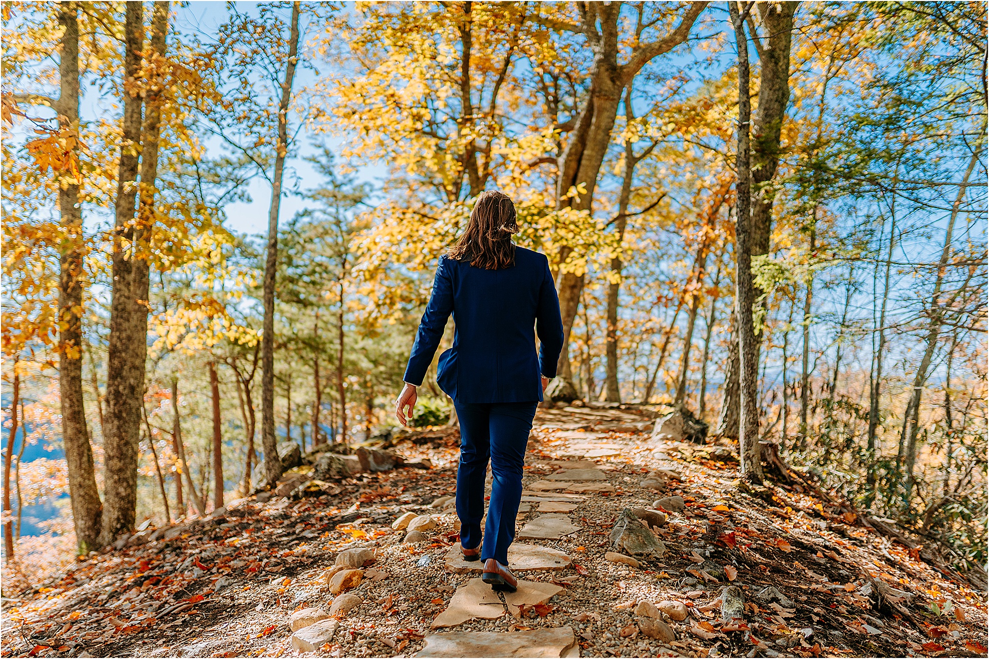 man in navy suit walking into woods