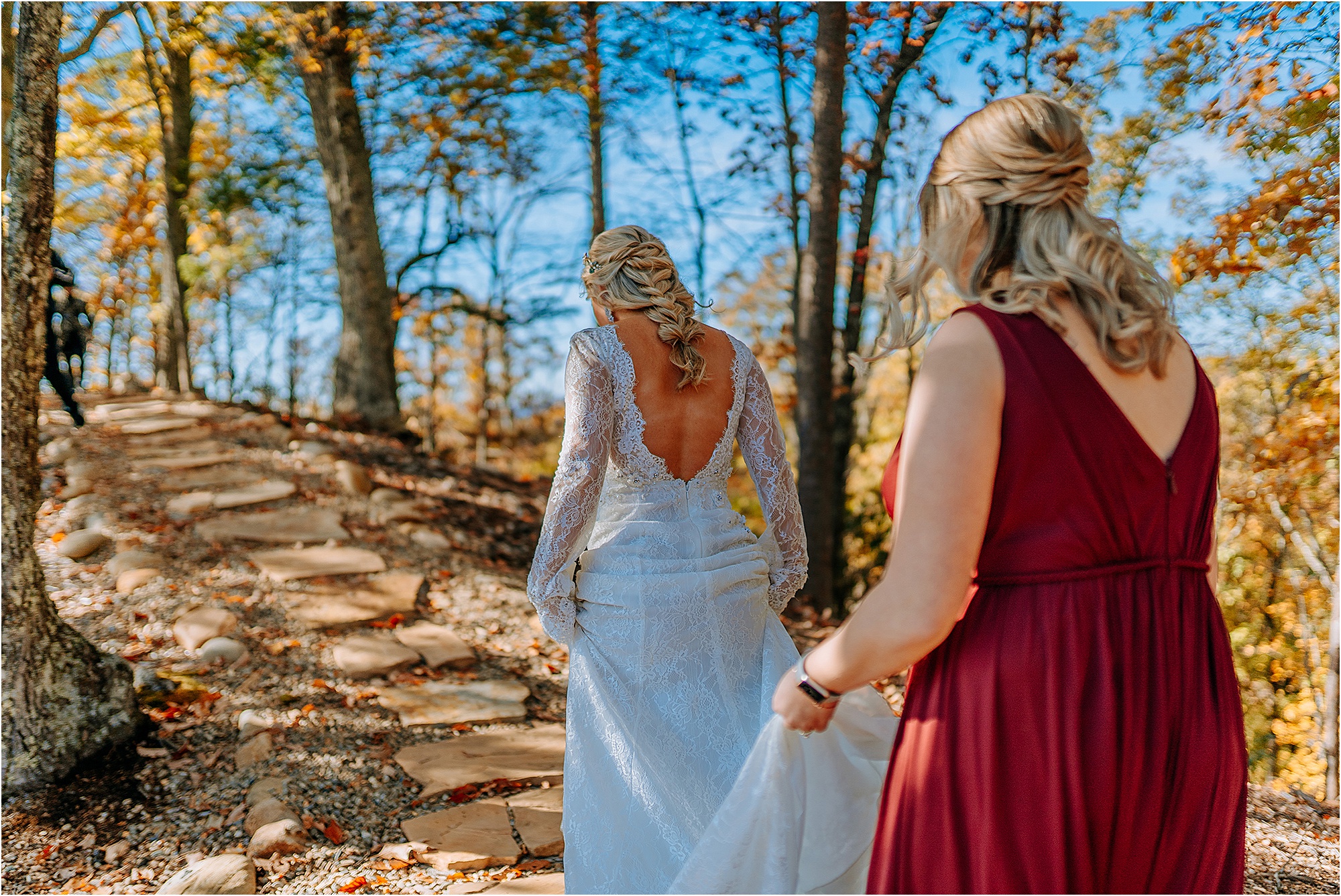 bride walking into woods with bridesmaid in burgundy dress