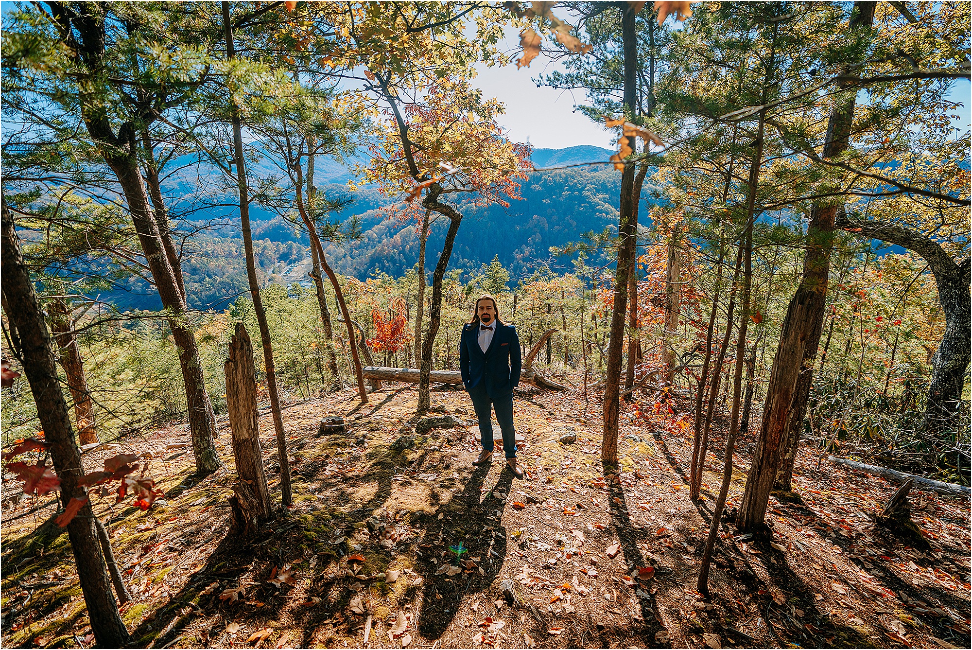 groom in navy suit standing on mountainside