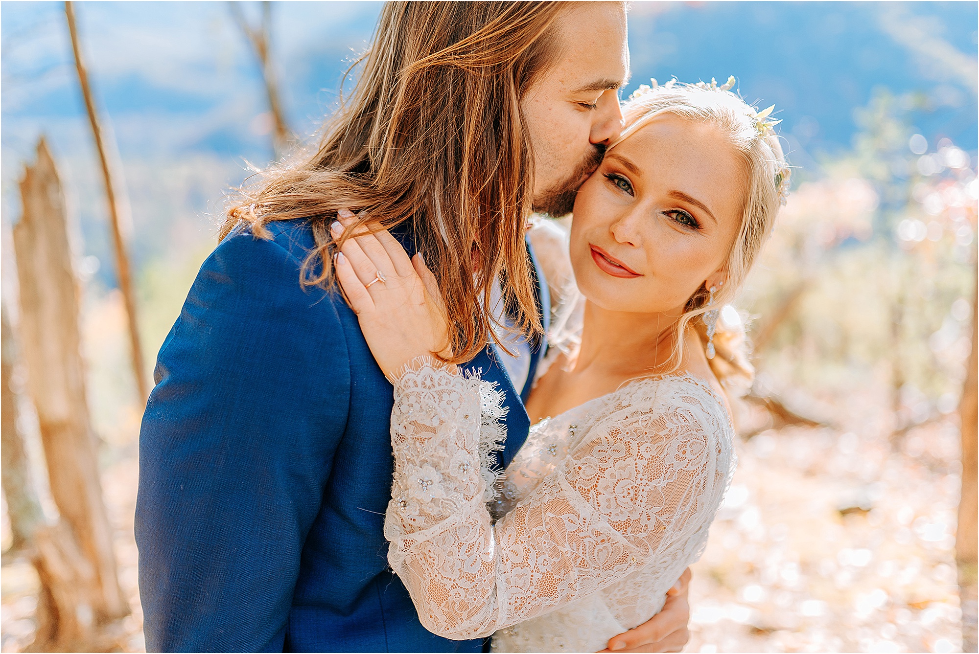 man in navy suit kissing bride on cheek