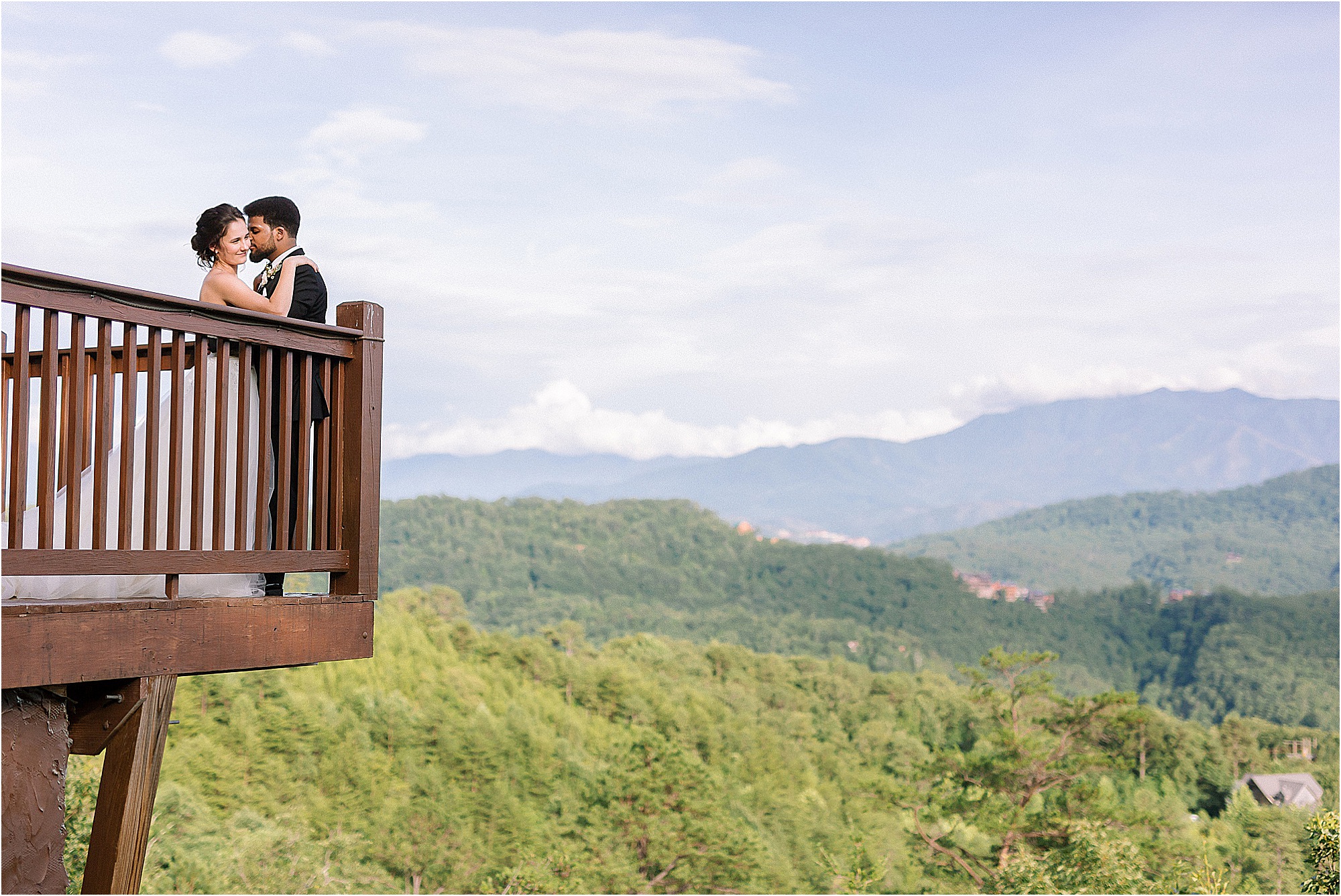 man and woman kiss on balcony overlooking mountains