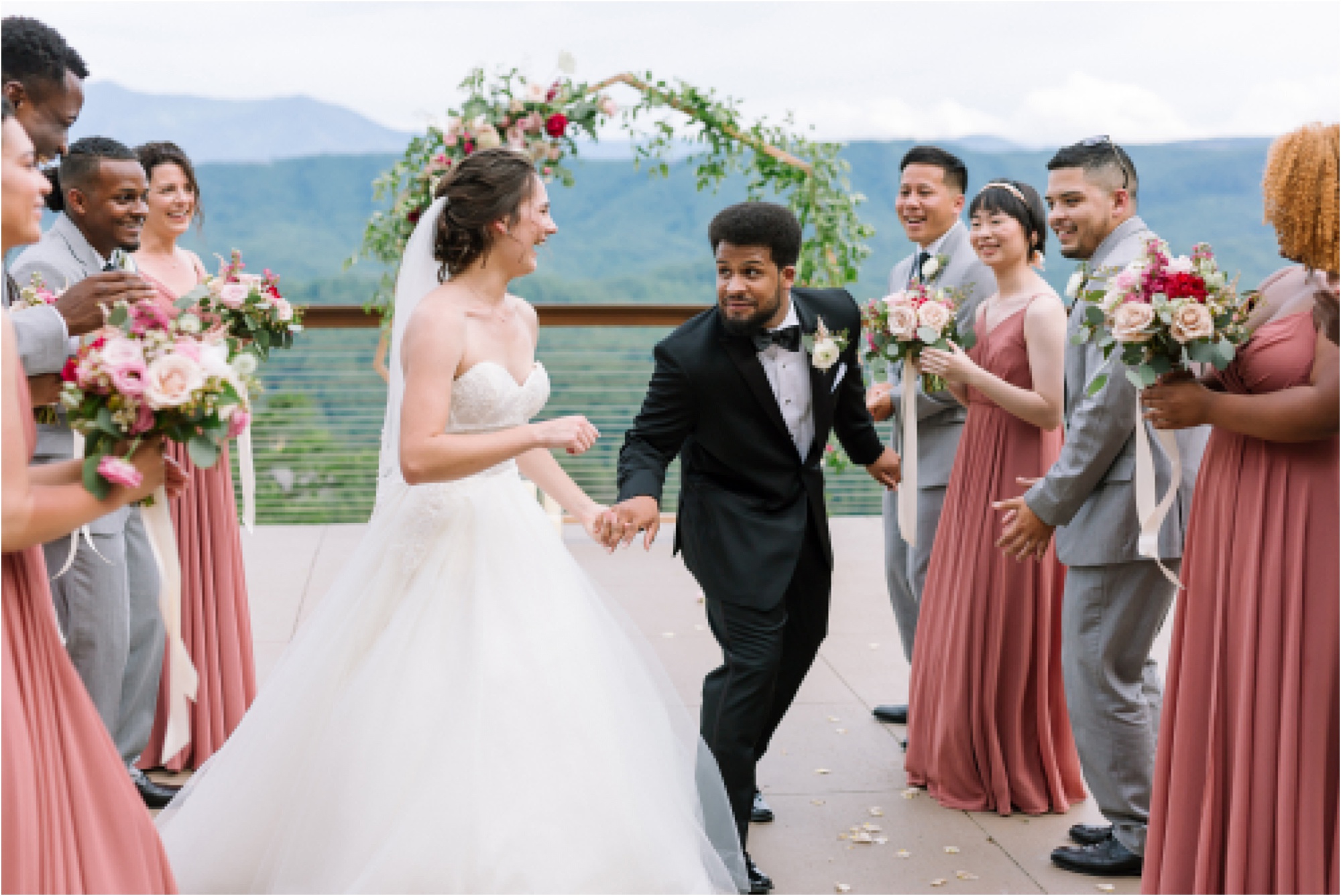 bride and groom walk between bridal party