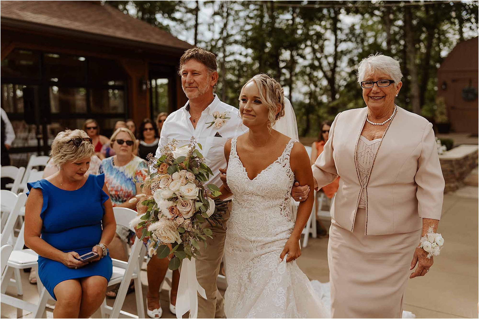 bride walking down aisle with mother and father at summer wedding