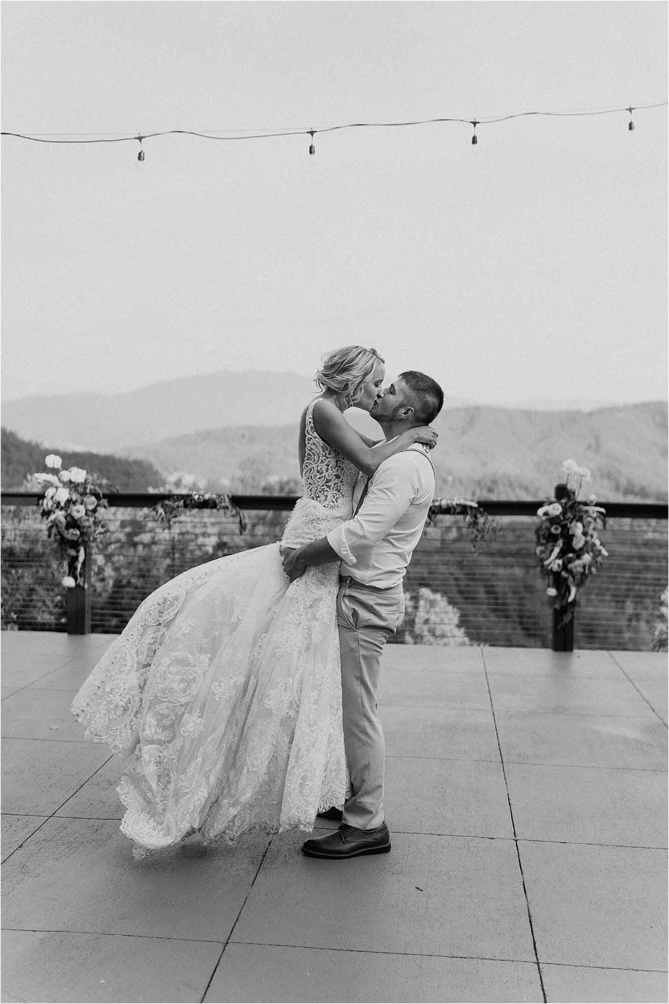 groom lifting up bride on mountainside patio