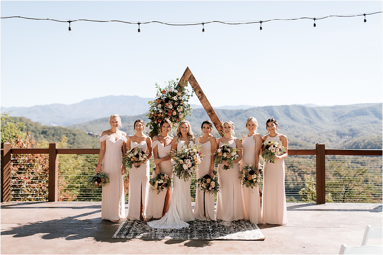 bride and bridesmaids standing under triangle wedding arch