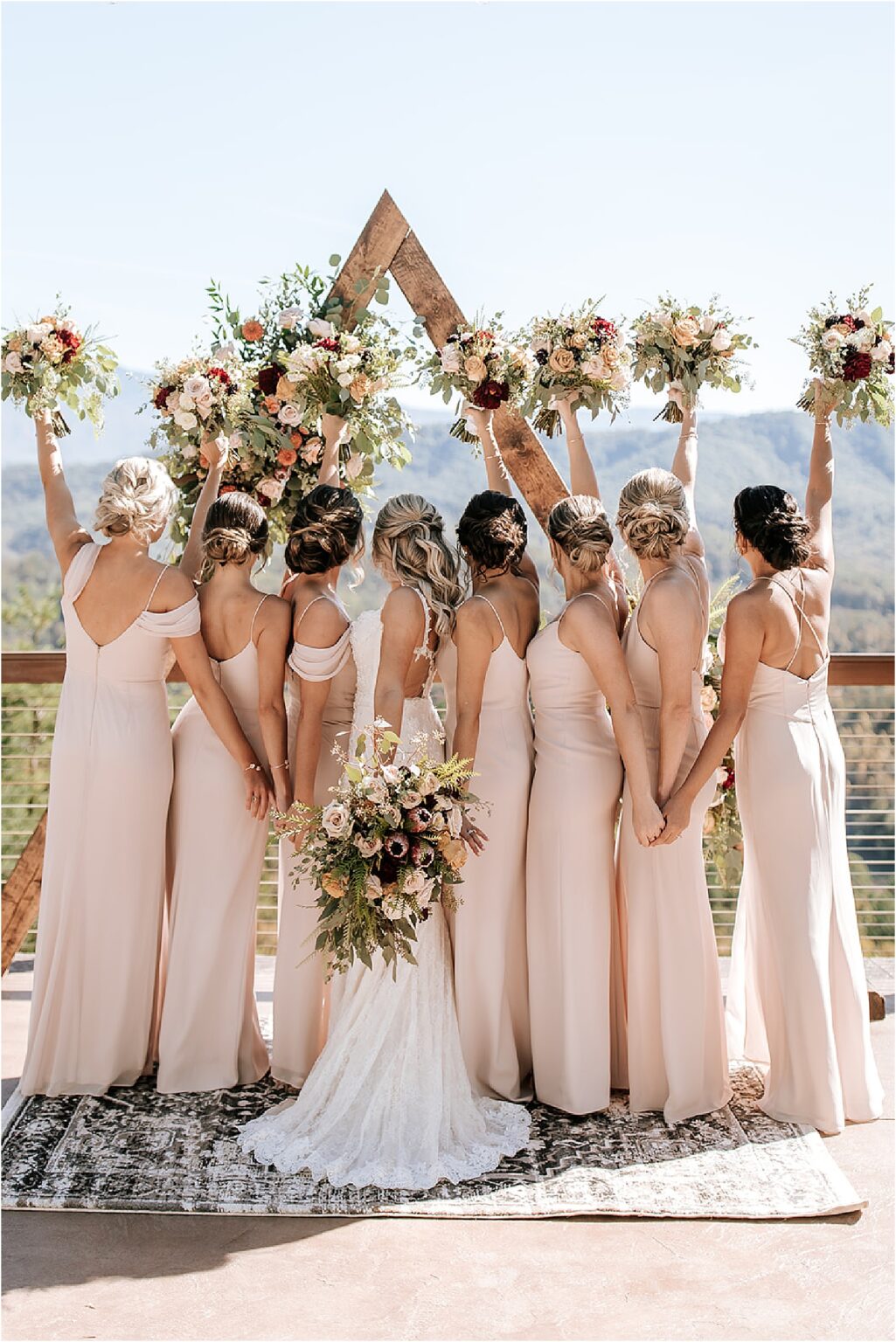 bride and bridesmaids raising bouquets for fun bridal party photo