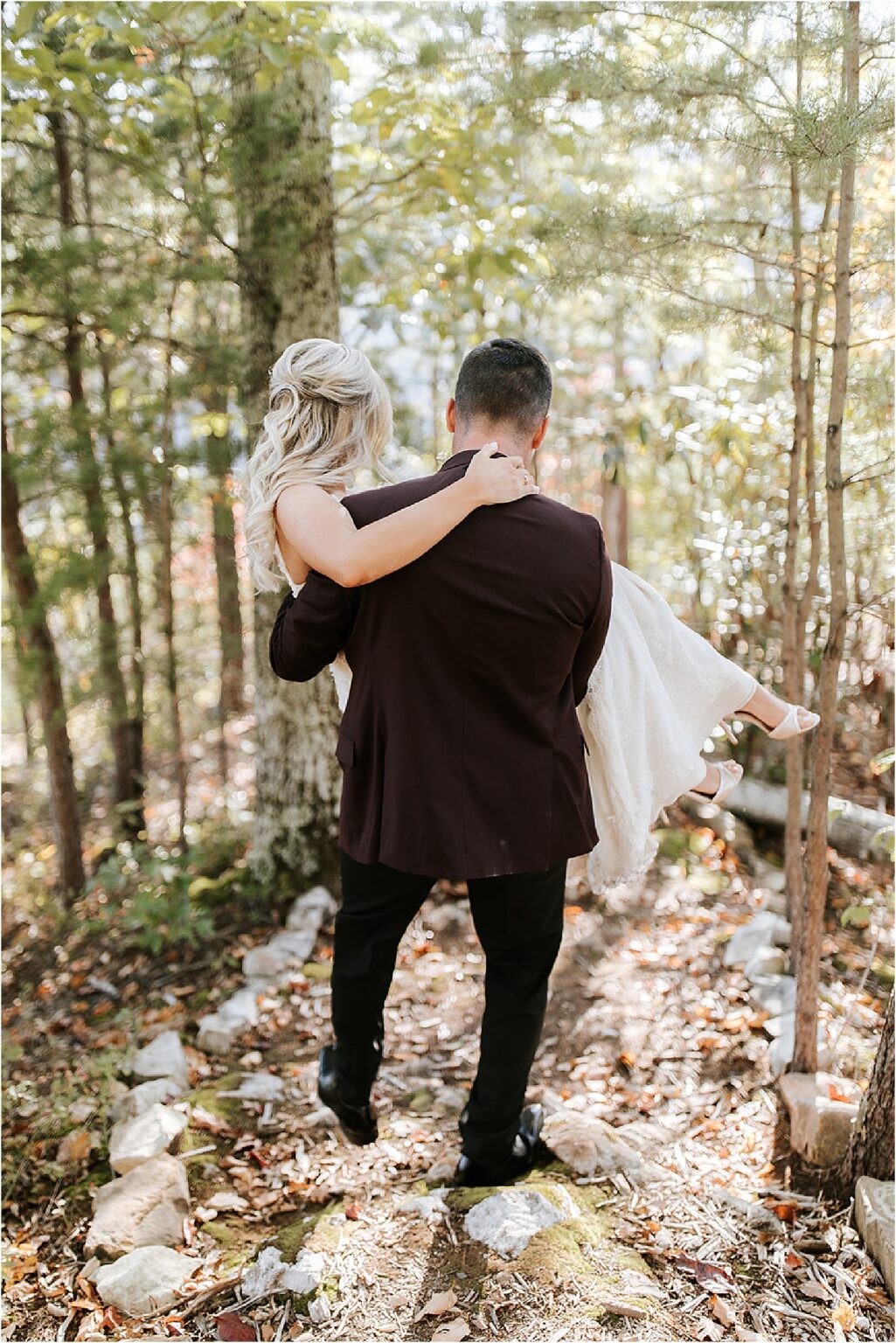 groom carrying bride in the woods