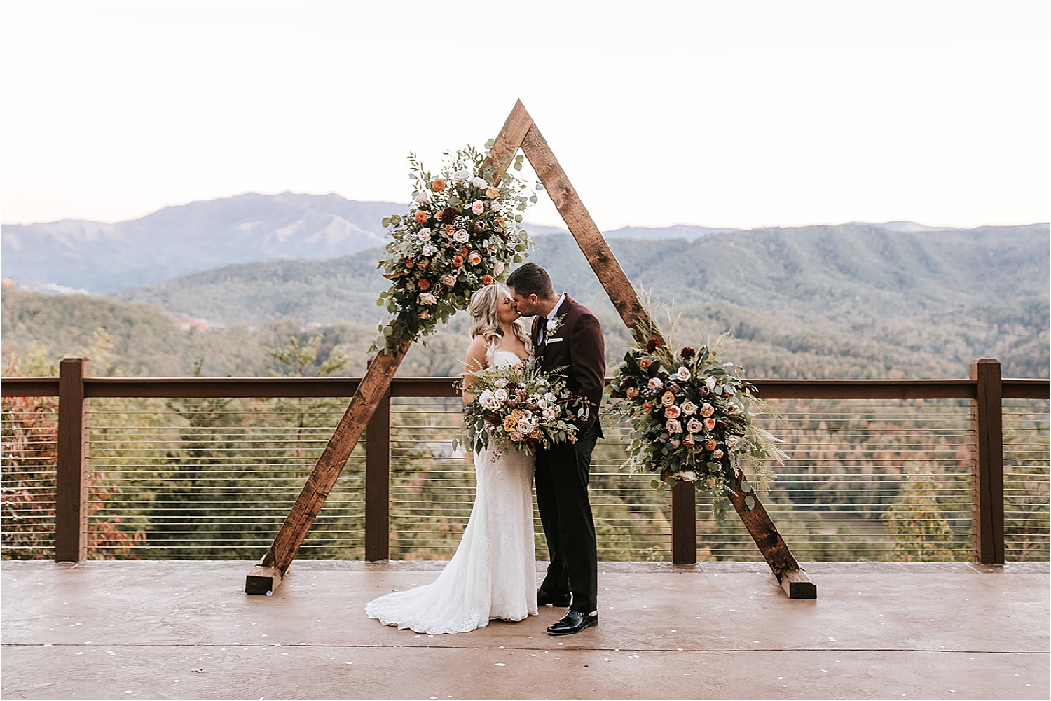 bride and groom kiss under triangle wedding arbor