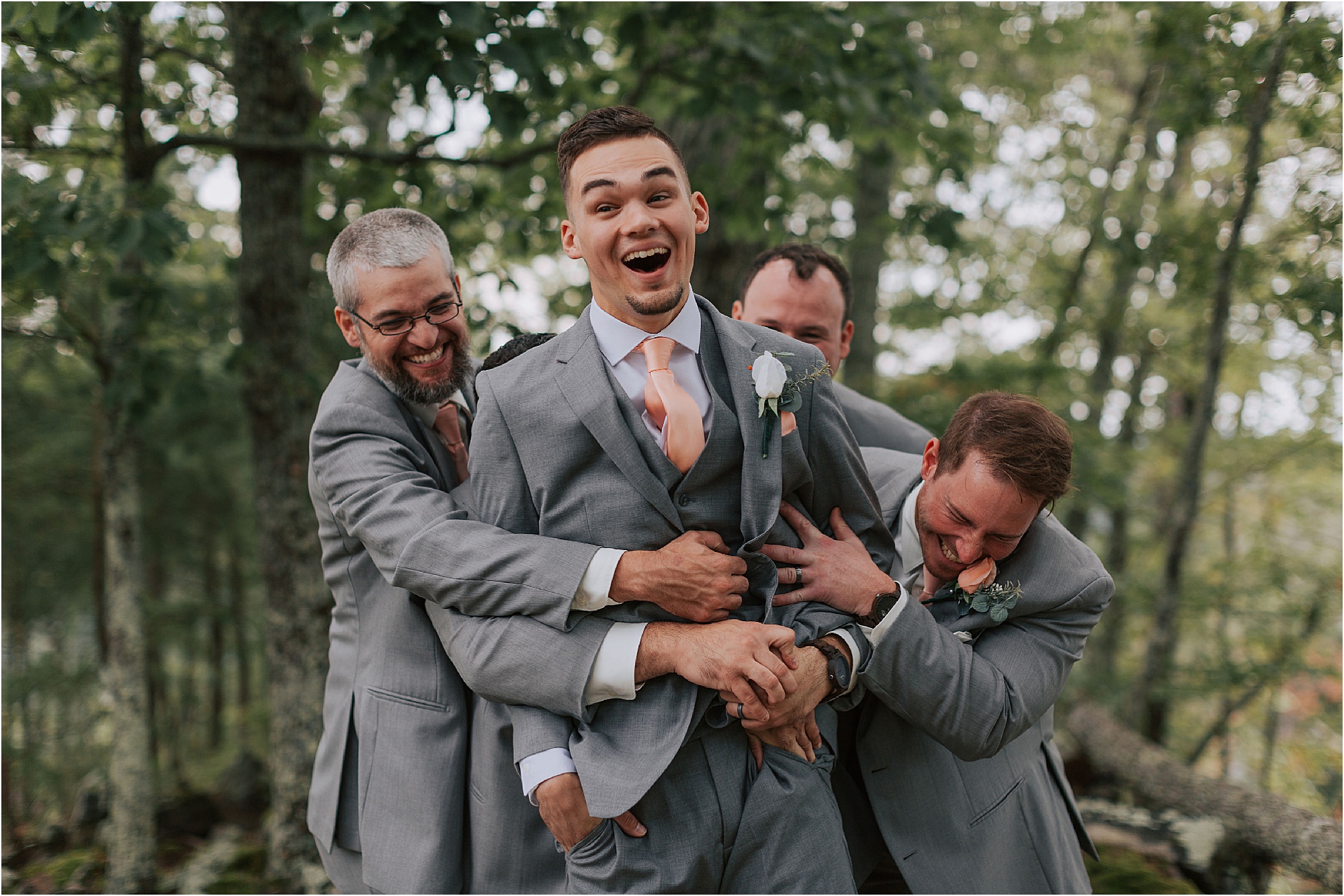 groomsmen in grey suits tackle groom