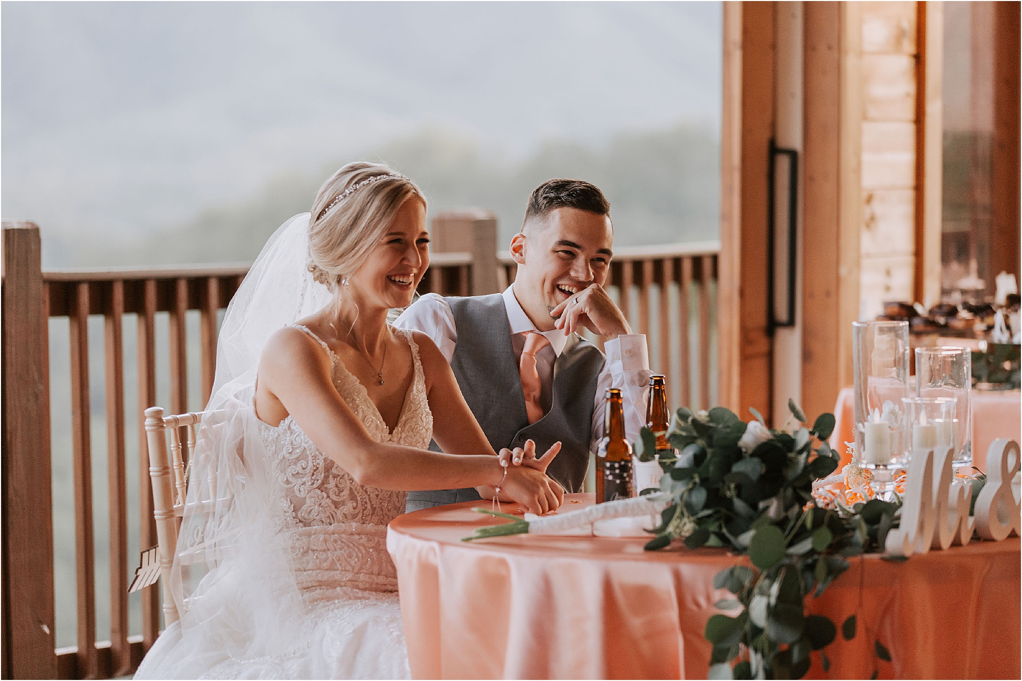 bride and groom laughing at sweetheart table during wedding toasts