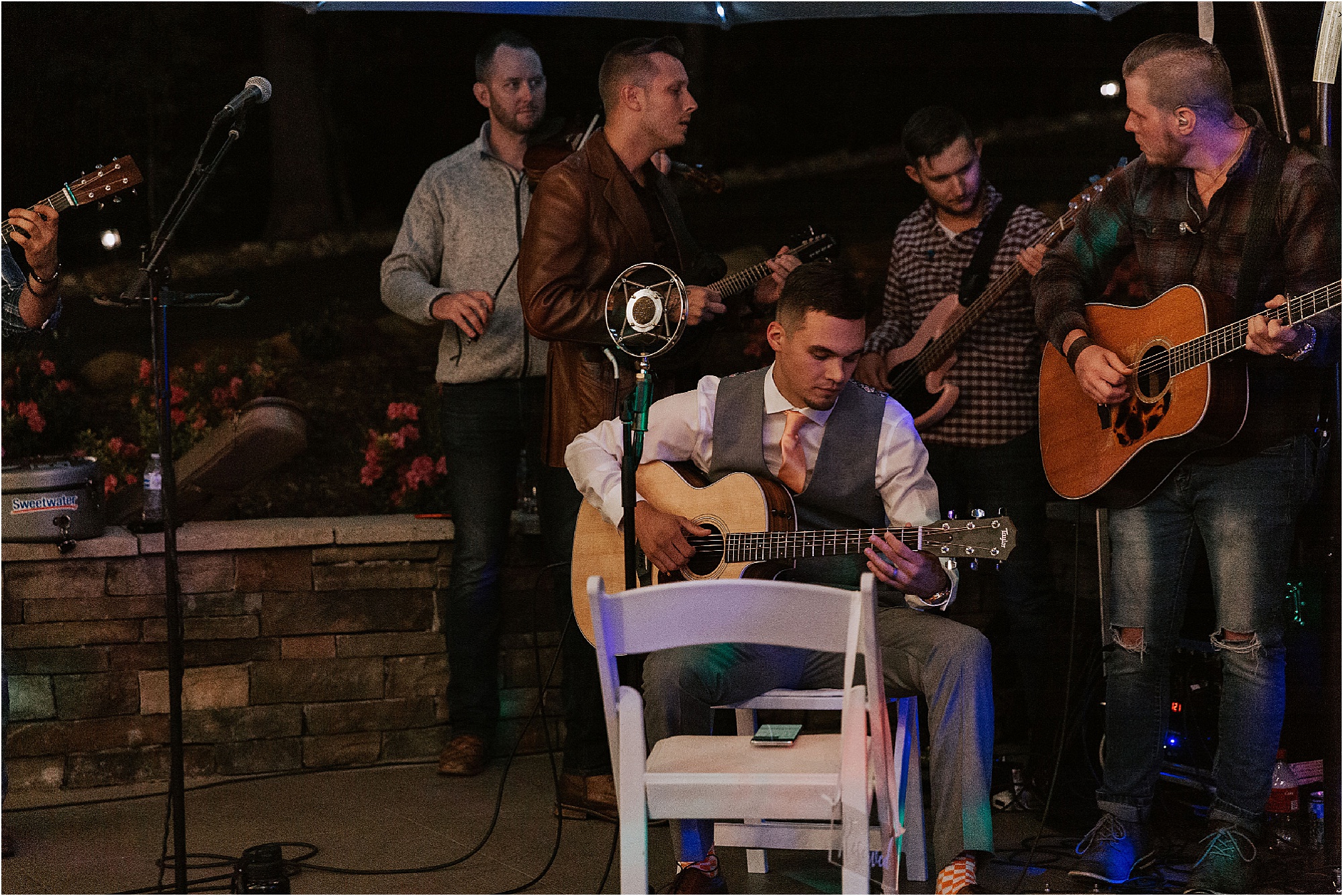 groom plays guitar at wedding reception