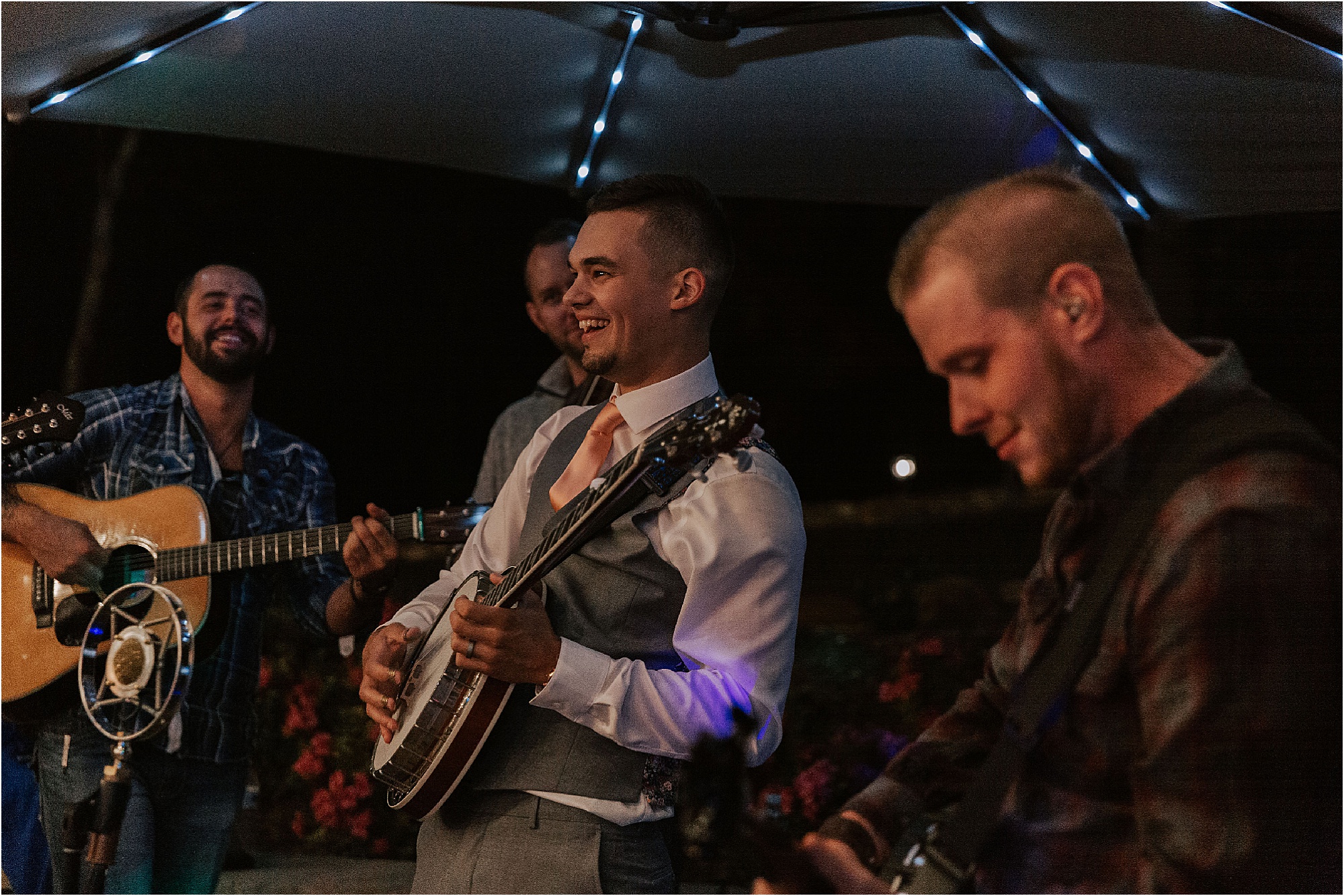 groom plays guitar at wedding reception
