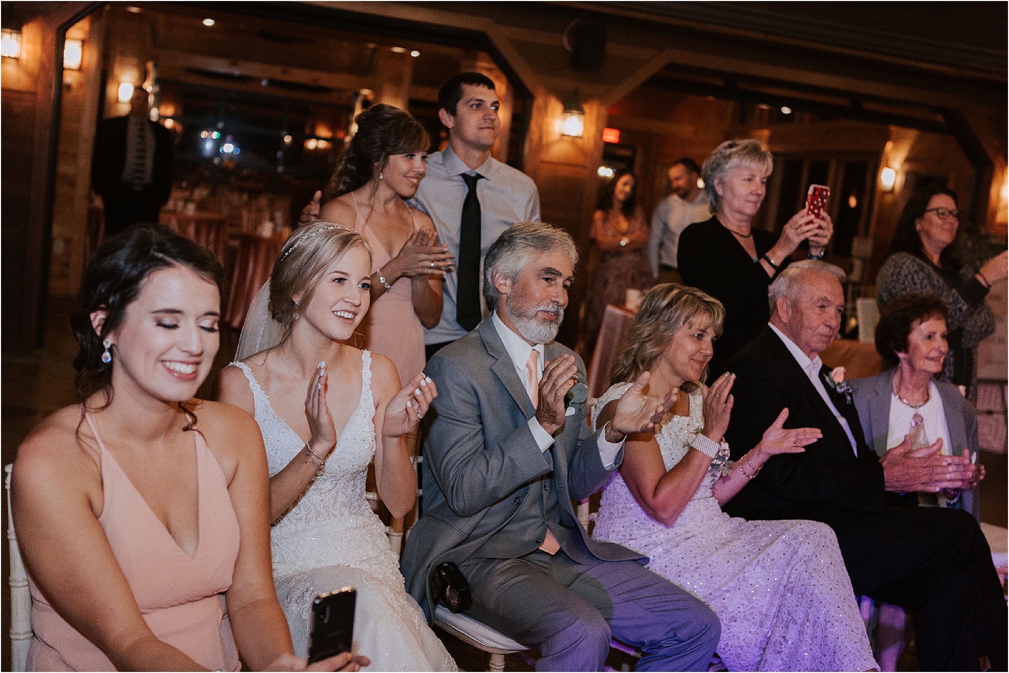 bride watches groom play guitar at wedding reception