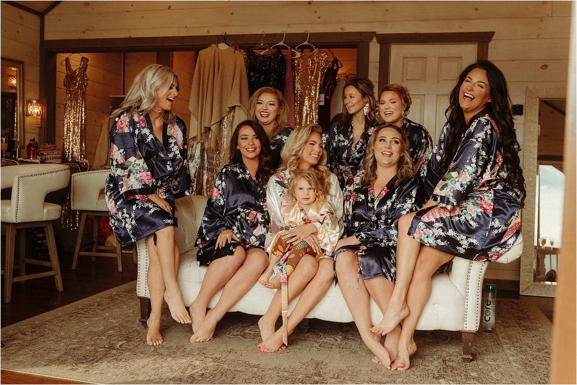 bride sitting on couch wearing robes with bridesmaids