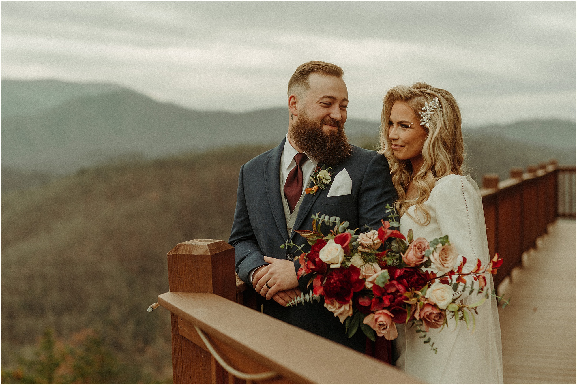 bride and groom stand at edge of wedding balcony overlooking the mountains