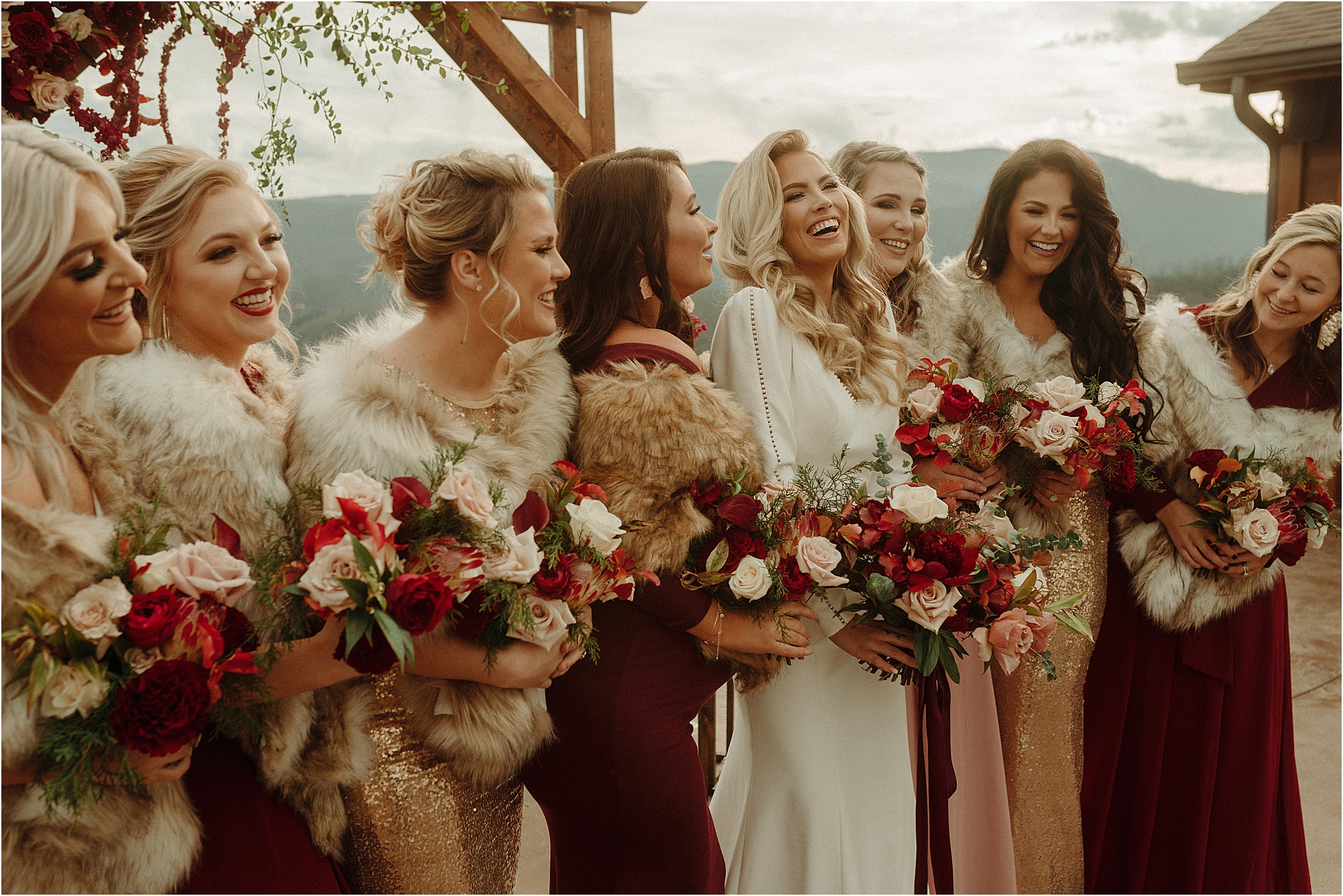 bride laughing with bridesmaids wearing faux fur shawls