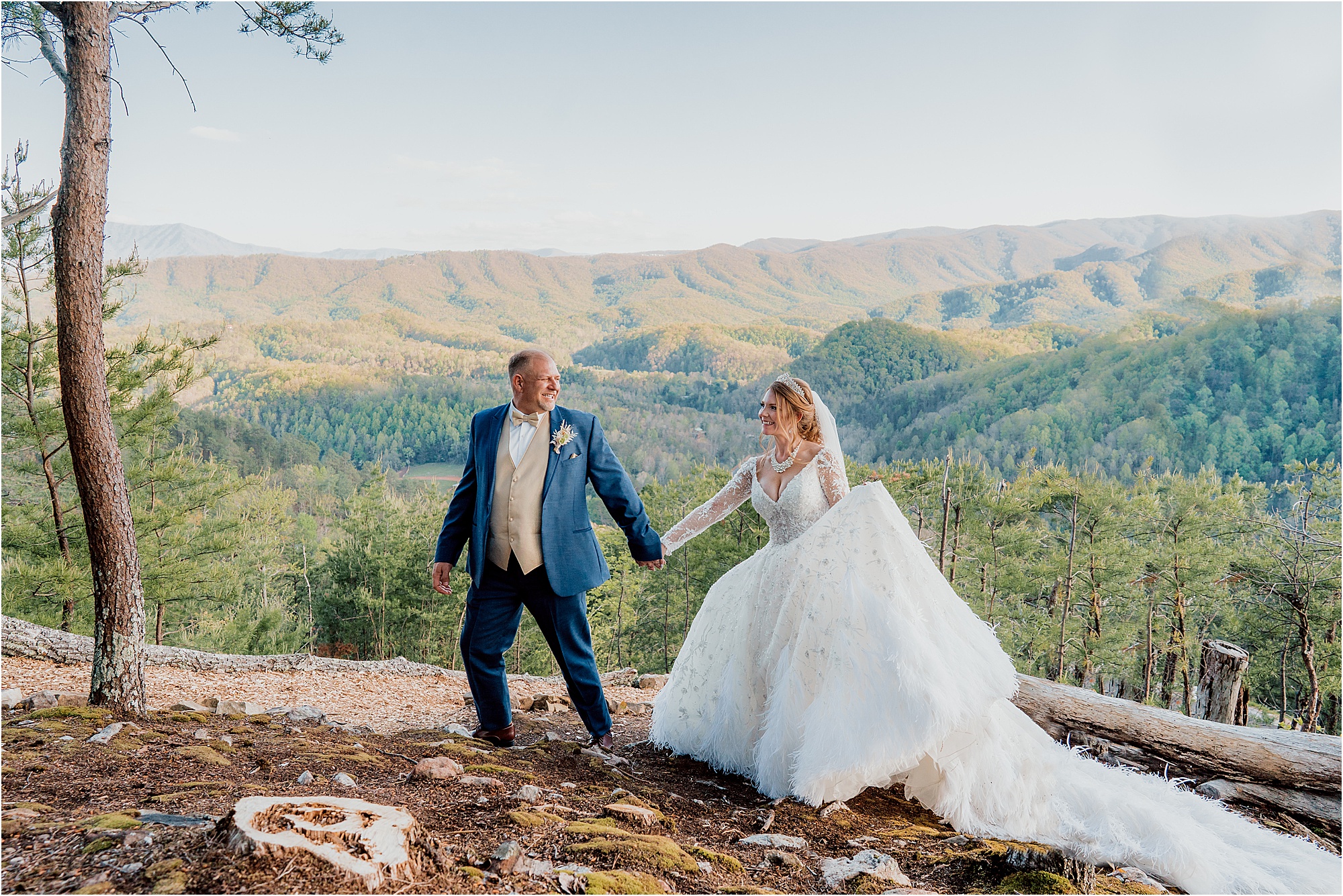 bride and groom walk across mountain in wedding attire