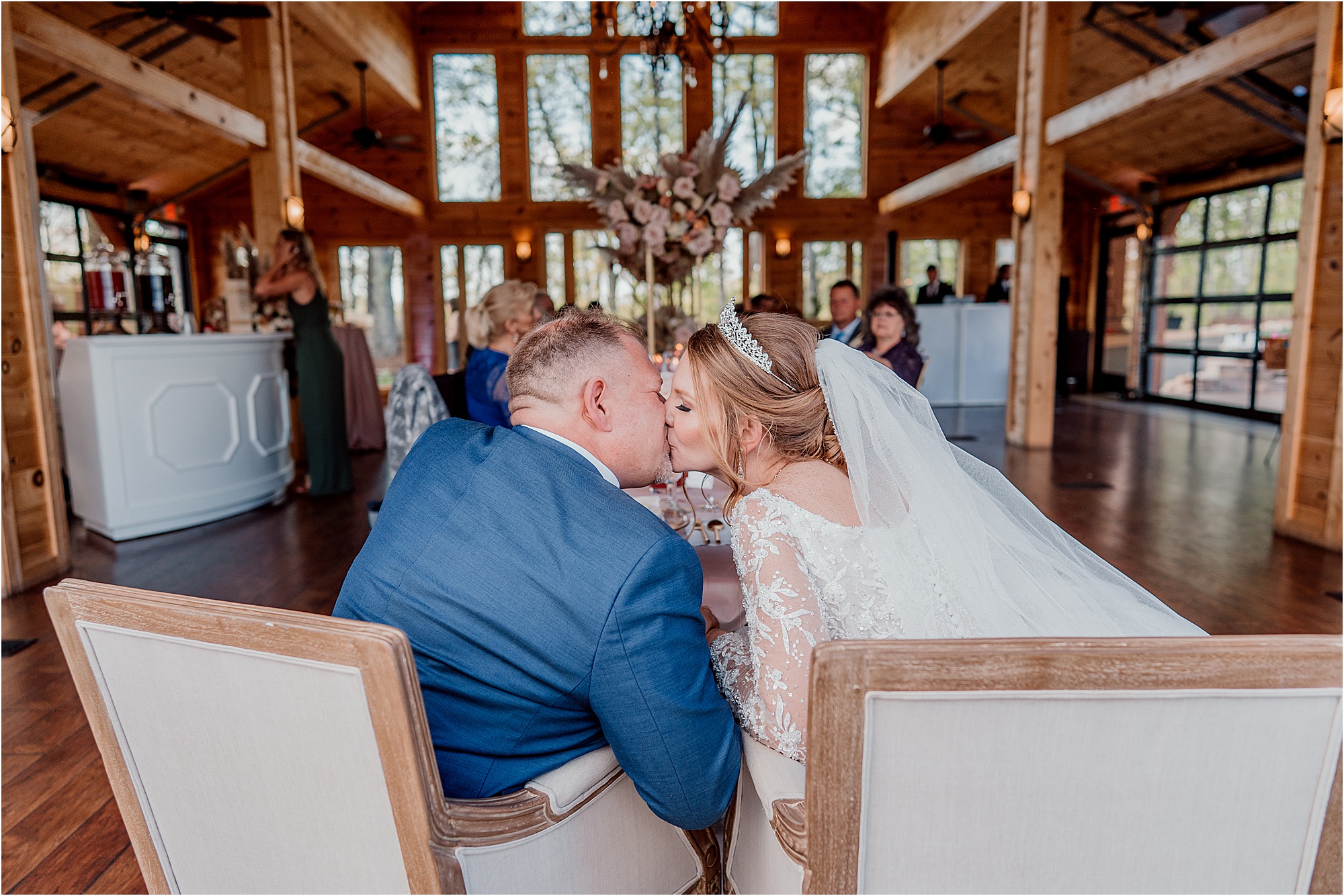 bride and groom kiss while sitting in wedding chairs