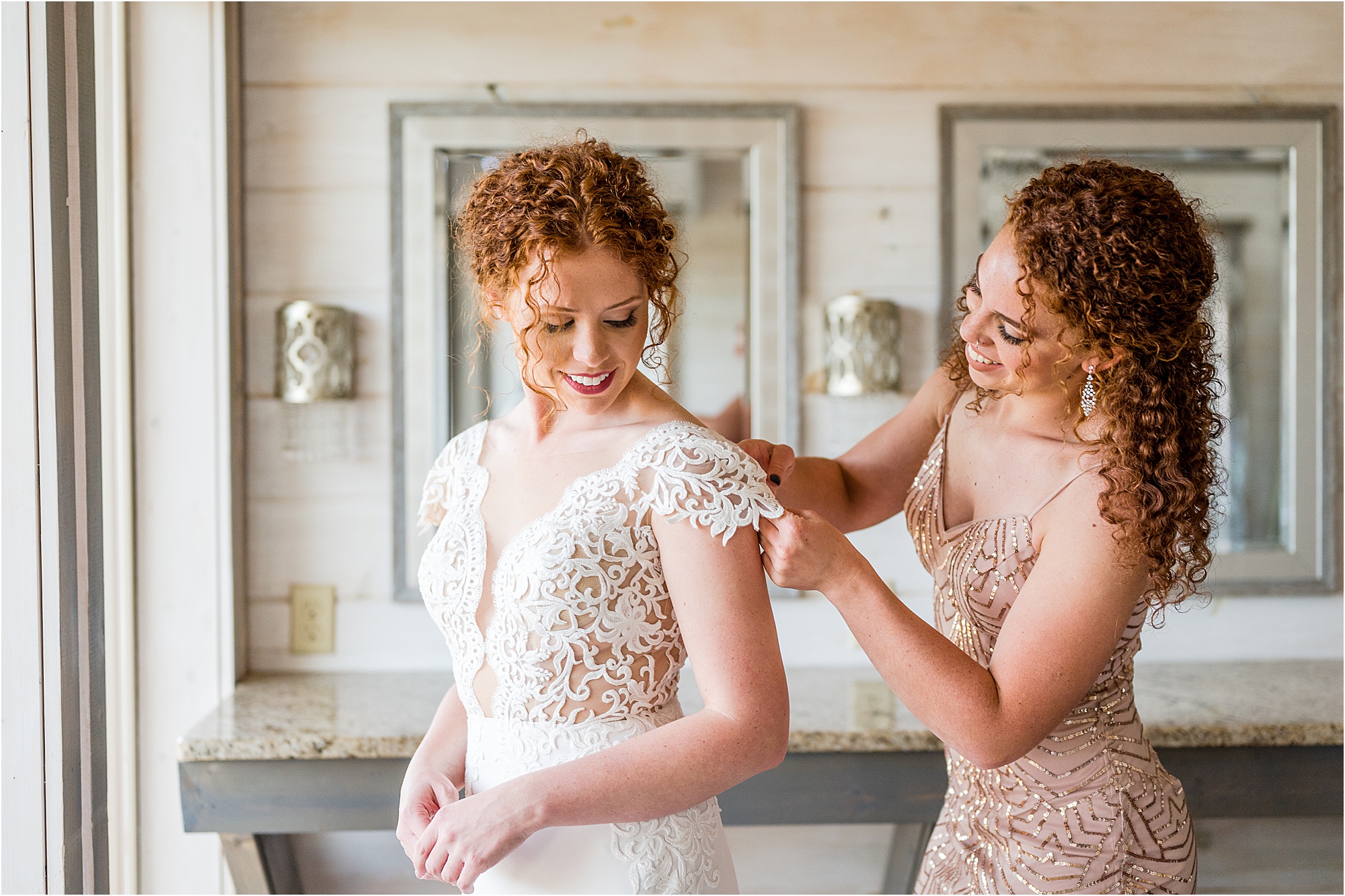 sister of the bride helping bride into dress