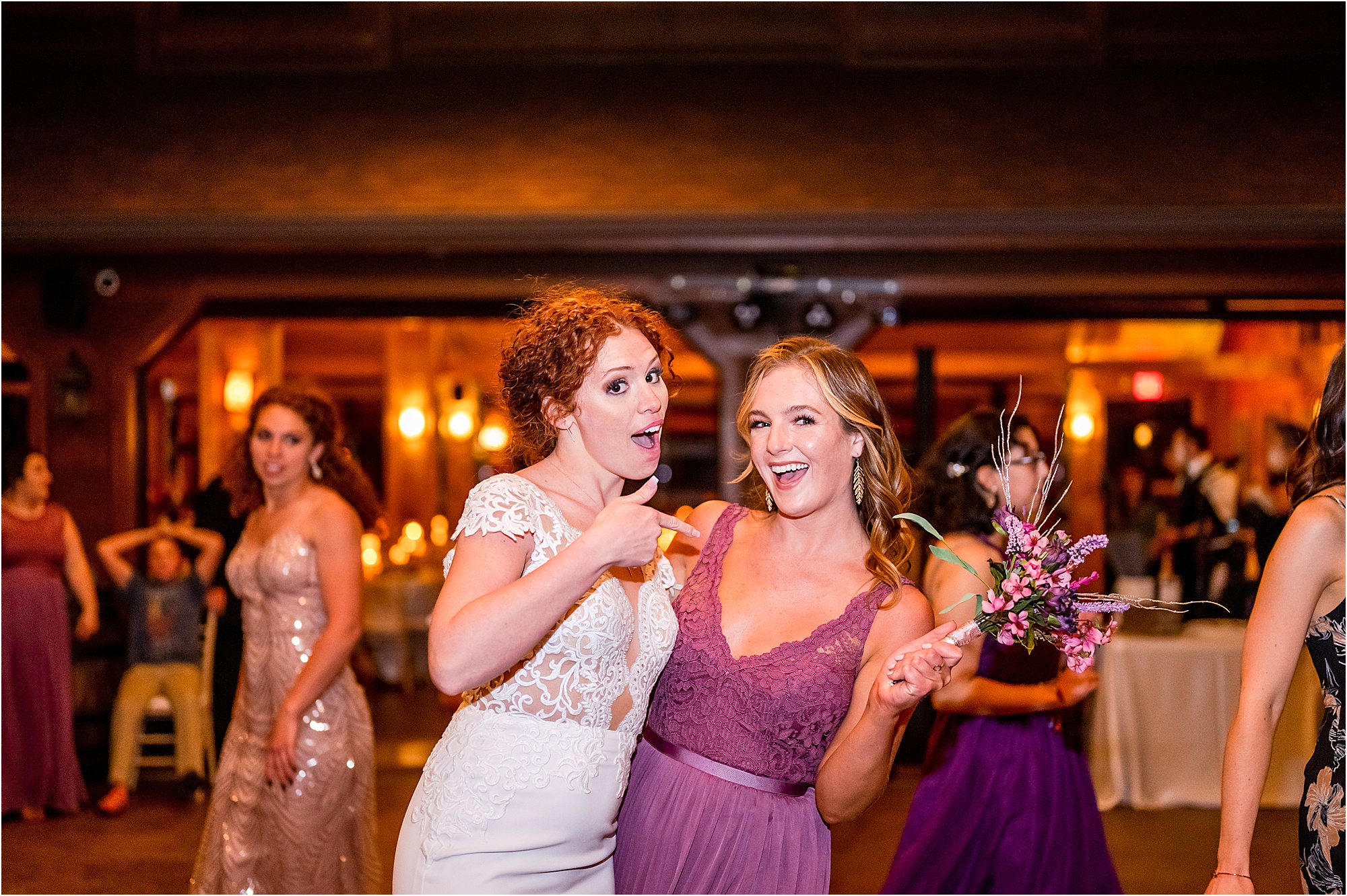 bride and bridesmaid pose for photo with wedding bouquet