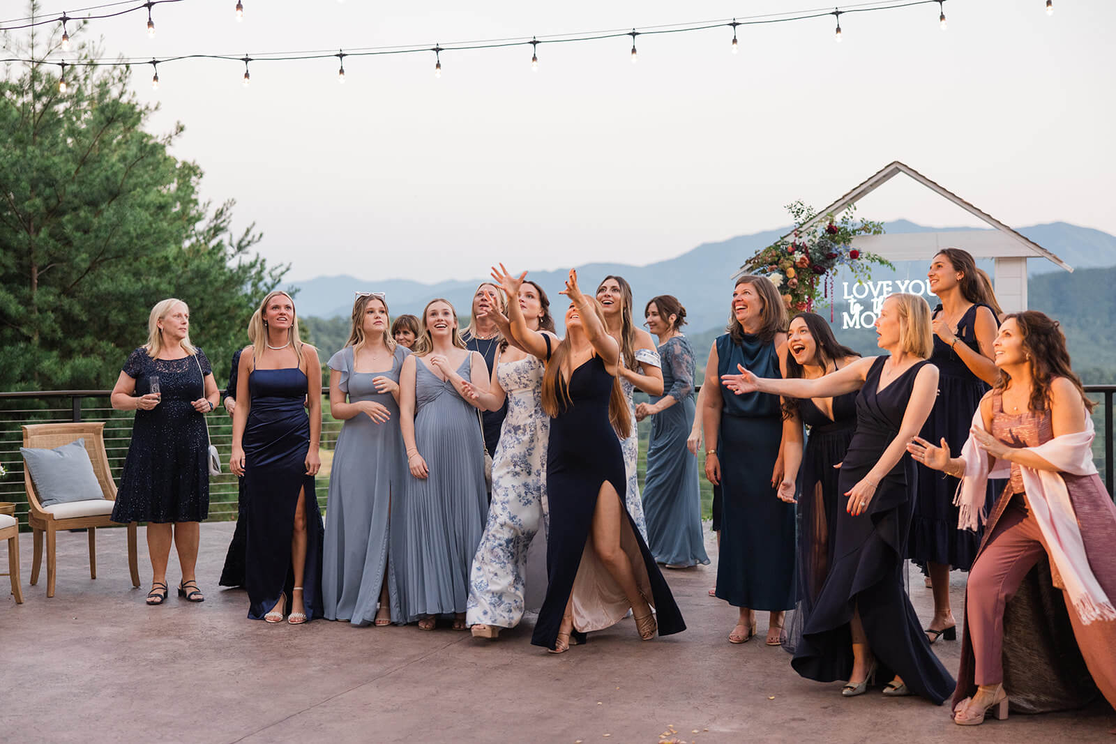 Evening reception under twinkling lights at The Magnolia Venue, bouquet toss a luxury Smoky Mountain wedding venue